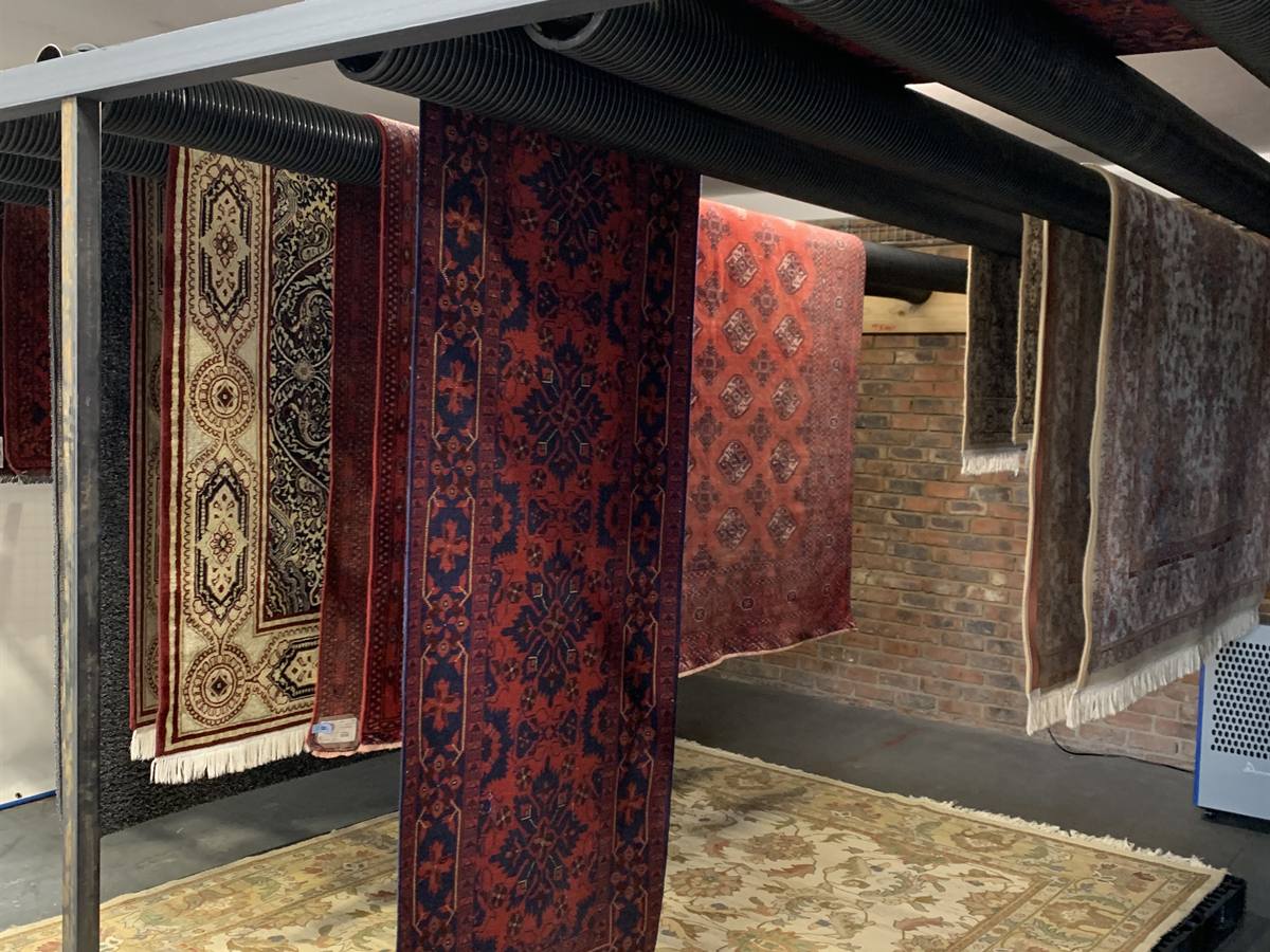 Washed rugs hanging over rails in the controlled drying room