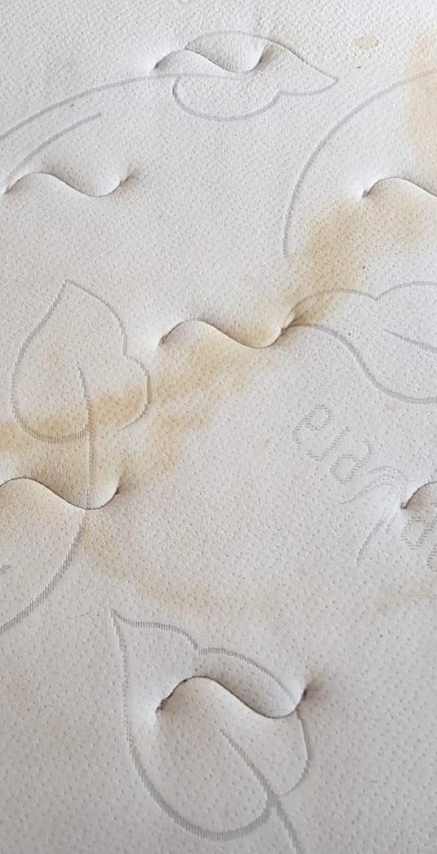A mattress before cleaning, marked and dulled